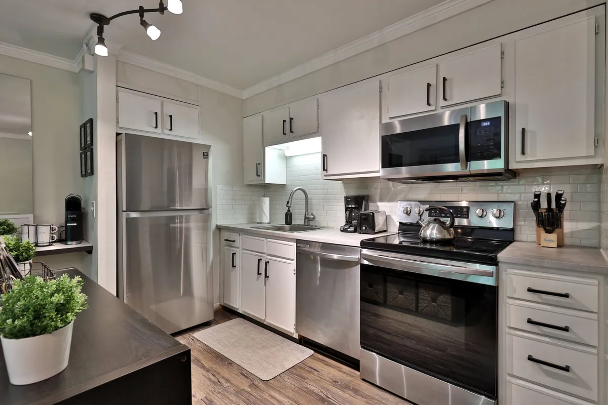 The kitchen is highlighted here with modern stainless steel appliances, a functional island, and tastefully decorated countertops. The setting is both welcoming and efficient, ready for group meal prep or casual entertaining.