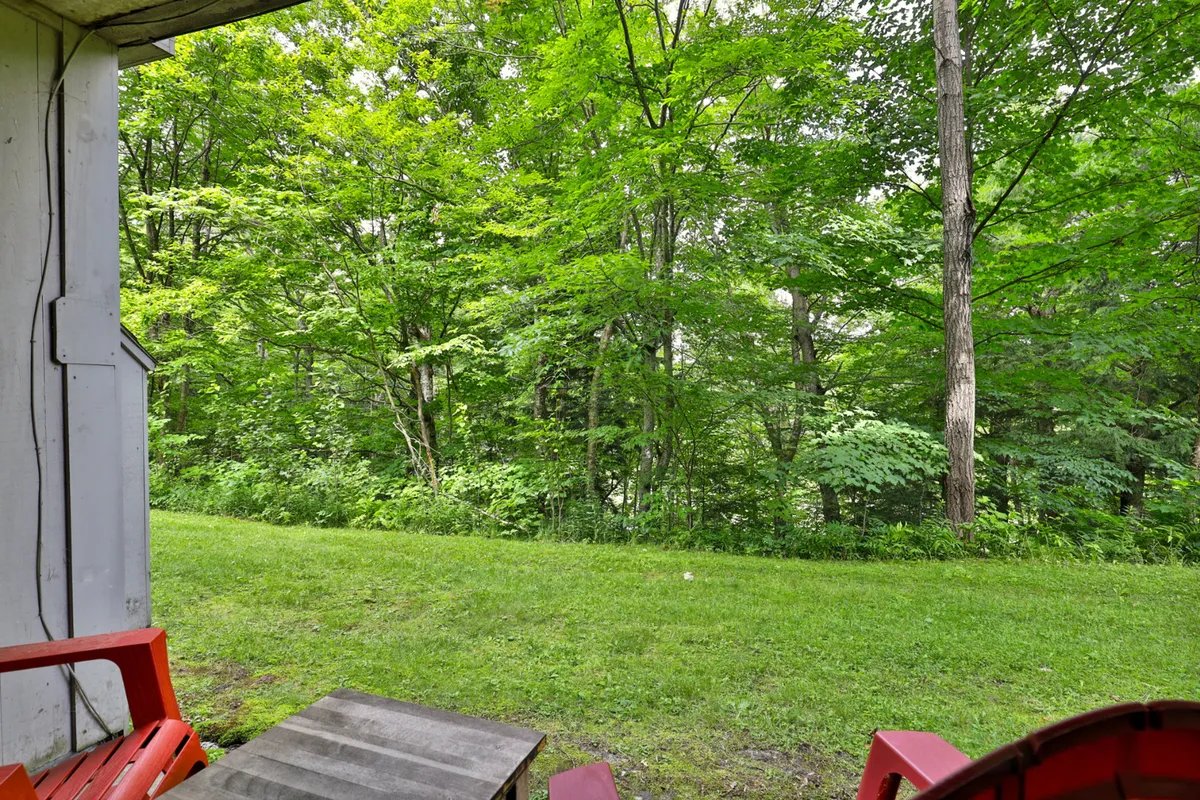 This image captures an outdoor scene with lush green trees, a well-kept lawn, and patio furniture set up for relaxation. The peaceful atmosphere suggests a tranquil retreat surrounded by nature, ideal for unwinding after outdoor adventures.